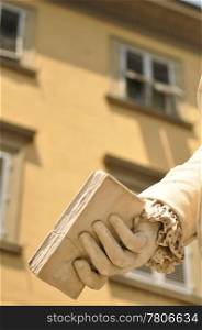 Book in the hands of a statue with building in the background