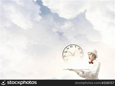 Book that blow up your imagination. Young woman in white hat with opened book in hands and clock on pages