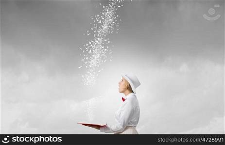 Book that blow up your imagination. Young woman in white hat with opened book in hands and characters flying out