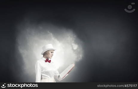 Book that develope your imagination. Young woman in white cylinder and red bowtie with book in hands