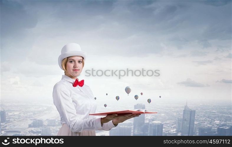 Book that develope your imagination. Young woman in white cylinder and red bowtie with book in hands