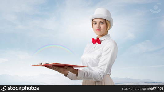 Book that develope your imagination. Young woman in white cylinder and red bowtie with book in hands