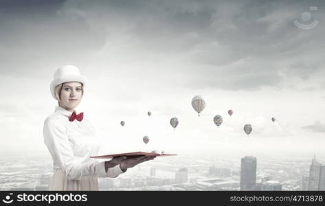 Book that develope your imagination. Young woman in white cylinder and red bowtie with book in hands