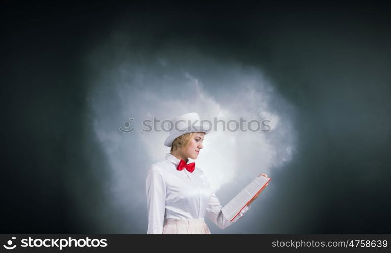 Book that develope your imagination. Young woman in white cylinder and red bowtie with book in hands