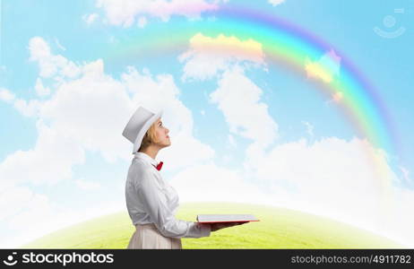 Book that develope your imagination. Young woman in white cylinder and red bowtie with book in hands