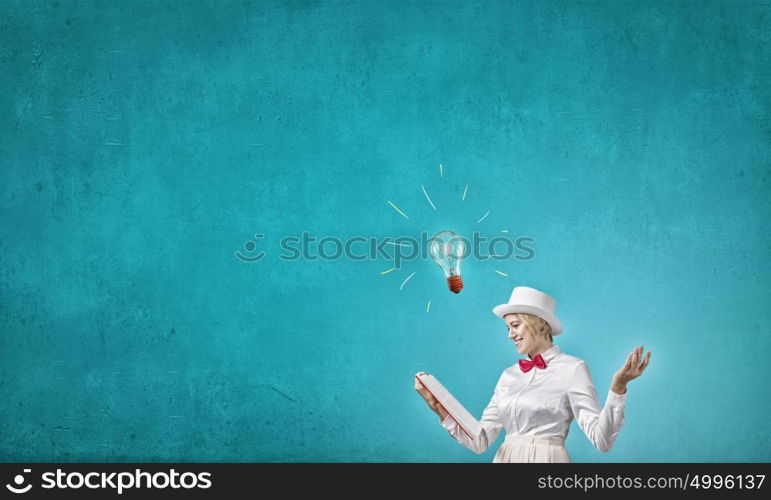 Book that develope your imagination. Young woman in white cylinder and red bowtie with book in hands