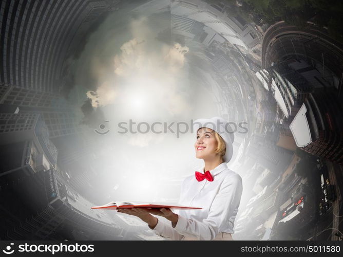 Book that develope your imagination. Young woman in white cylinder and red bowtie with book in hands