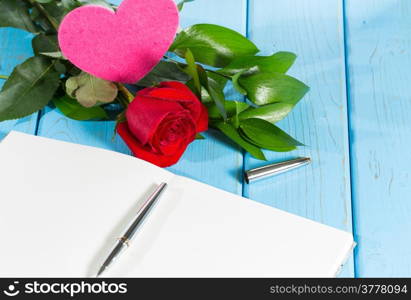 Book with a rose on top of an antique table in blue