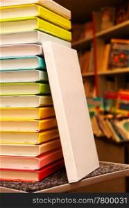 Book with white cover staying at stack of colorful books