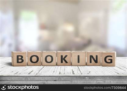 Booking sign on a wooden desk in a room with a bright blurry background