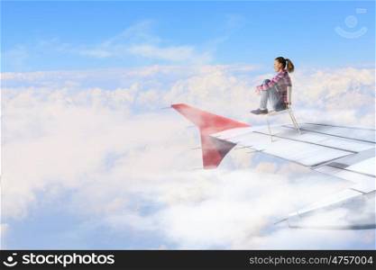 Booking Vacation Online. Teenager girl in chair on edge of airplane wing