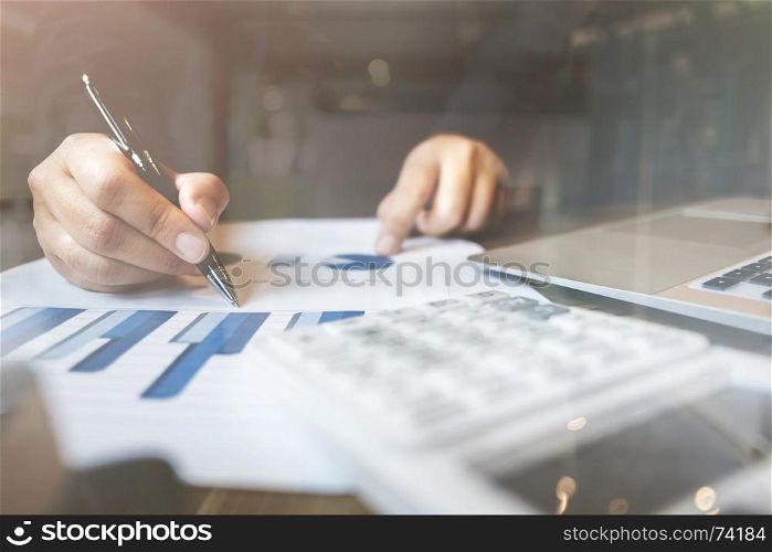 bookkeeper / financial inspector calculating on investment data with documents and laptop in dark office room