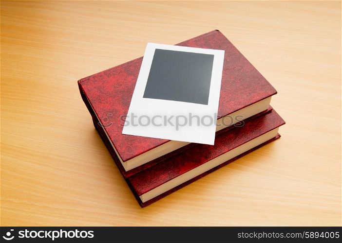 Books and blank photos on wooden table