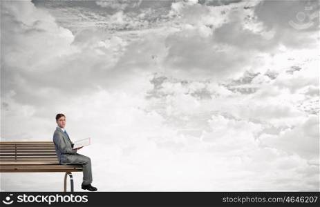 Books broden your mind. Young businessman sitting on bench with book in hands