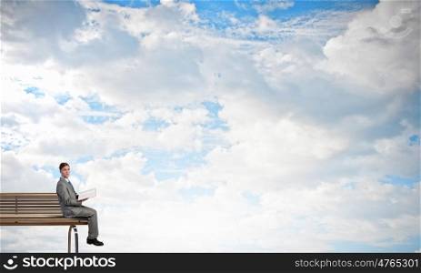 Books broden your mind. Young businessman sitting on bench with book in hands