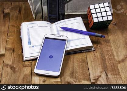 Books, diary with pen, smartphone and cube Rubik lie on a wooden surface