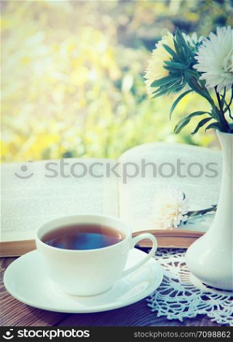 Books, flowers and white cup on wooden table