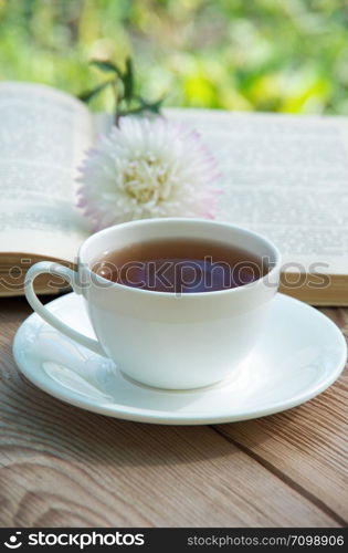 Books, flowers and white cup on wooden table