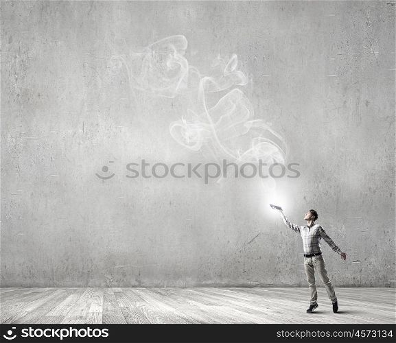 Books let you rise above the rest. Young handsome man in concrete room reaching hand with book