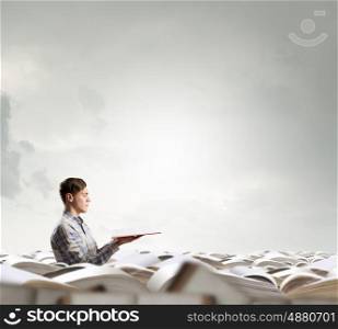 Books let you rise above the rest. Young handsome man in pile reaching hand with book