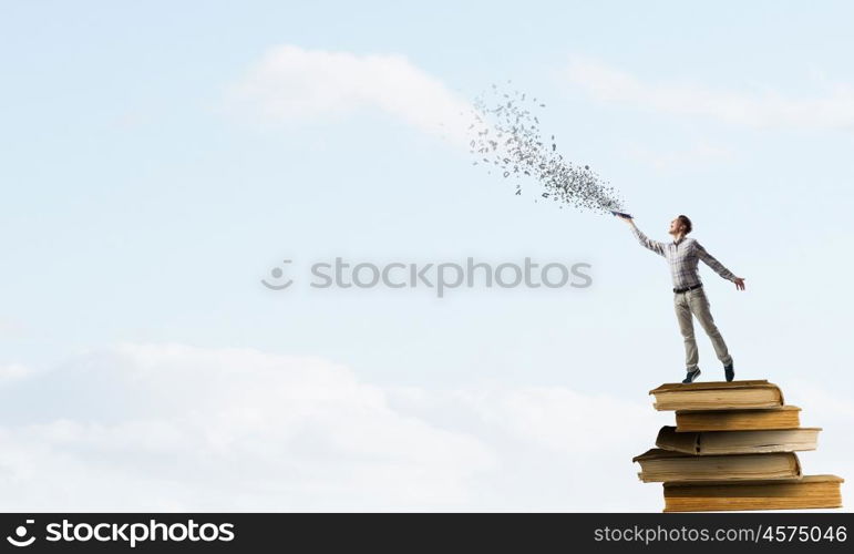 Books let you rise above the rest. Young handsome man on stack reaching hand with book