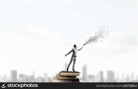 Books let you rise above the rest. Young handsome man on stack reaching hand with book