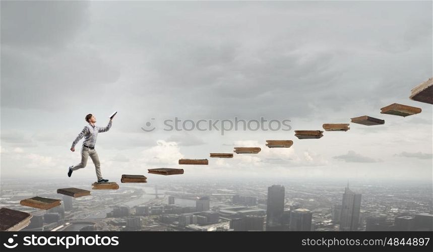 Books let you rise above the rest. Young man running with book in reached hand