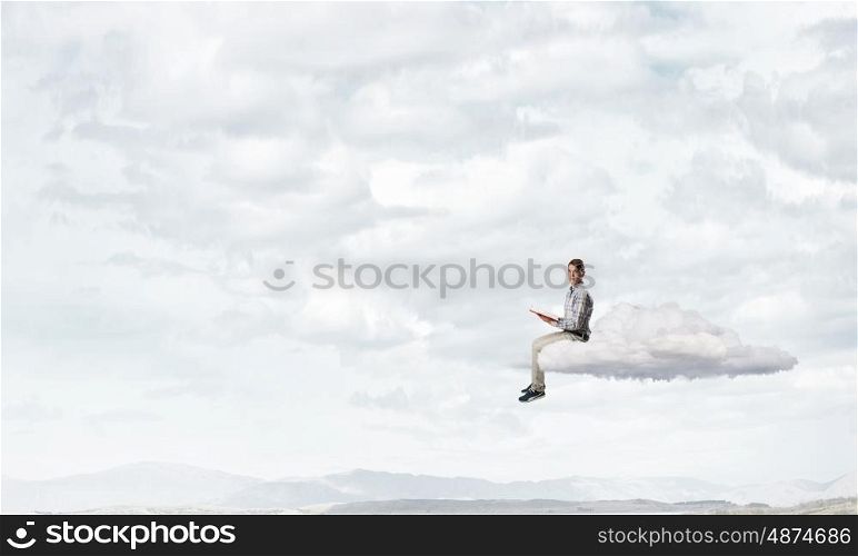Books let you rise above the rest. Young student man floating on cloud and reading book