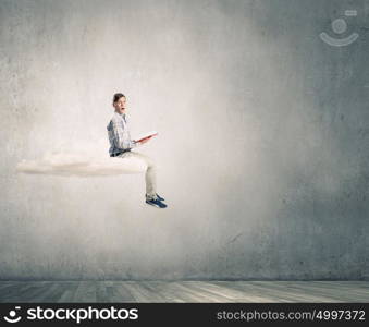 Books let you rise above the rest. Young student man floating on cloud and reading book