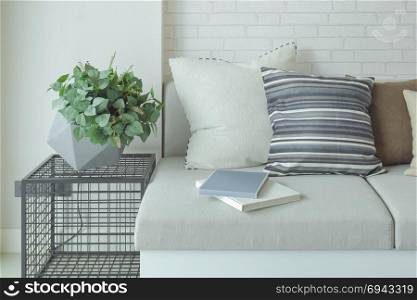 Books on sofa with flower pot on side table