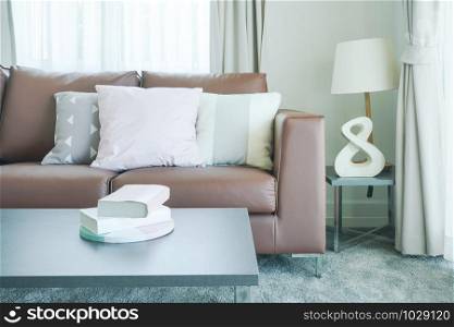 Books on table and brown sofa with pillows in the living room
