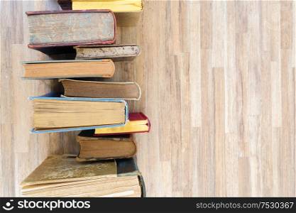 Books row on wooden table, top view flat lay. Reading, learning, literature concept. Pile of old books