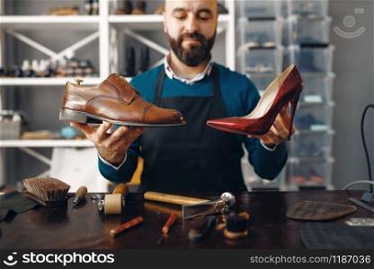 Bootmaker shows repaired shoes, footwear repair service. Craftsman skill, shoemaking workshop, master works with boots, cobbler job