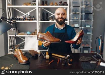 Bootmaker shows repaired shoes, footwear repair service. Craftsman skill, shoemaking workshop, master works with boots, cobbler. Bootmaker shows repaired shoes, footwear repair