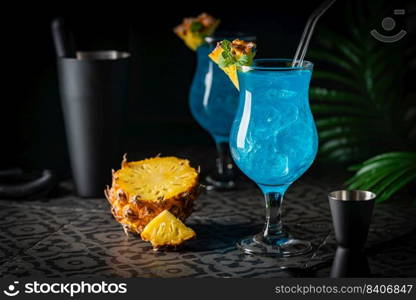 Boozy Blue Hawaii Cocktail with Rum and Pineapple on black background. Boozy Blue Hawaii Cocktail
