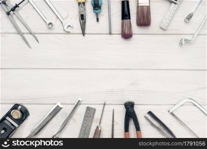 Border frame of work tools on white wooden table with copy space. Top view