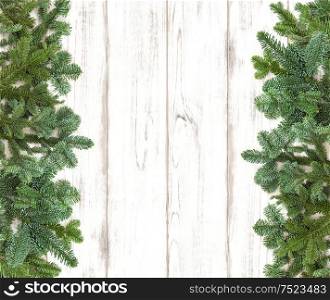 Border from pine tree branches on wooden background. Winter holidays decoration