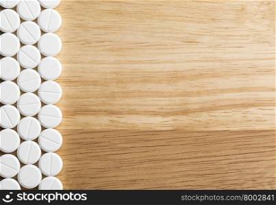 Border from white pills with copy space. Border from white pills on a wooden background.Top view