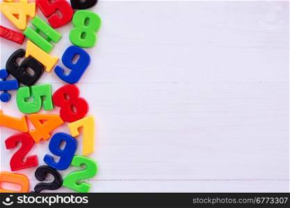 Border of colorful toy magnetic numbers with copy-space on wooden background