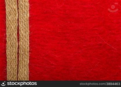 Border or frame formed by rough burlap rope over red textile background.