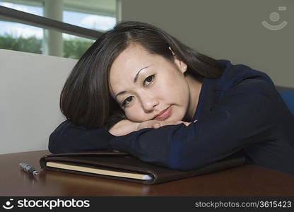 Bored Asian Businesswoman with Head on Desk