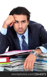Bored businessman sat with pile of paperwork