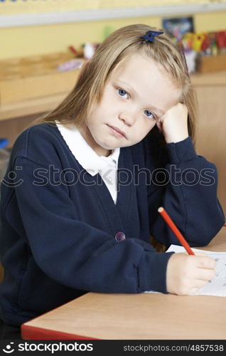 Bored Female Elementary School Pupil At Desk