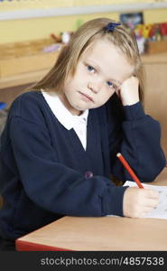 Bored Female Elementary School Pupil At Desk