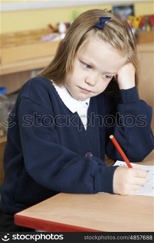 Bored Female Elementary School Pupil At Desk