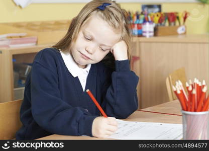 Bored Female Elementary School Pupil At Desk