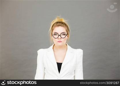 Bored focused or grumpy blonde college teacher or office orker woman wearing nerdy eyeglasses, white jacket.. Bored focused college woman teacher wearing eyeglasses