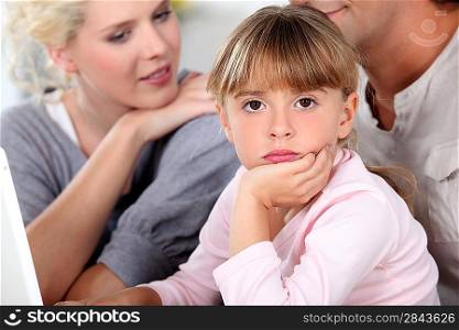 Bored little girl sat with her parents