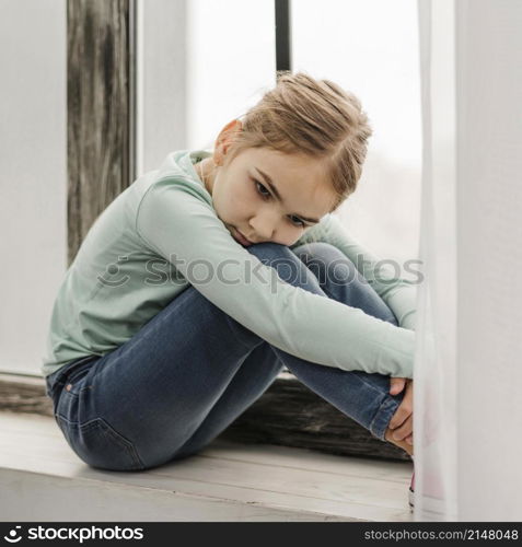 bored little girl sitting window sill