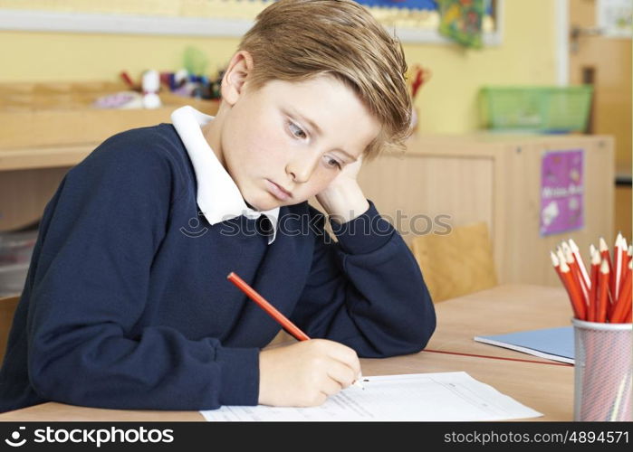 Bored Male Elementary School Pupil At Desk